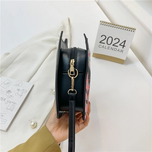Sac à bandoulière chic en cuir PU noir avec imprimés roses et détails latéraux ailés