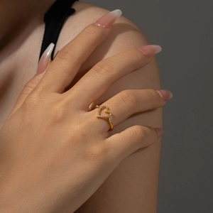 Detailed macro shot of a heart-shaped gold ring with pavé-set white zircons on a hand