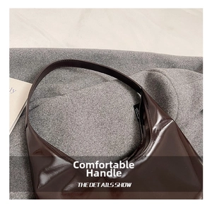 Detail of a dark brown glossy patent leather shoulder bag with a comfy handle