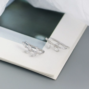 Detail of S925 silver leaf earrings with marquise-cut crystals on an open book