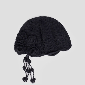 Close-up of handmade crochet cloche hat with floral detail and hanging tassels