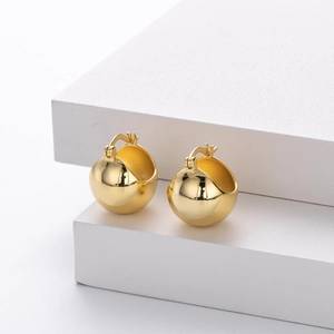 Detail of polished golden S925 sterling silver ball earrings on a white display stand