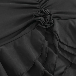 Detailed close-up of obsidian black mesh fabric with 3D floral decoration and ruffles