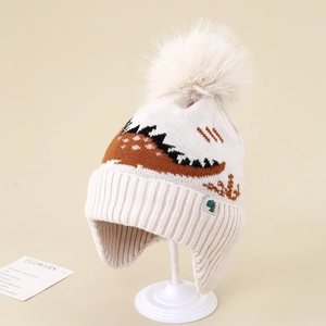 Close-up of children winter knit hat with pom-pom and jacquard dinosaur pattern