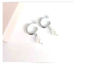 Macro detail of silver C-shaped hoop earrings with baroque pearls on white background
