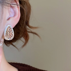 Detail of leaf-shaped earrings with leopard print and silver-finished metallic frame
