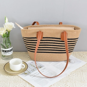 Close-up of woven straw tote bag featuring contrast stripes and leather handles