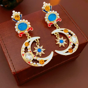 Detailed shot of vintage gold earrings with blue gems, pearls, moon and star motifs on leather