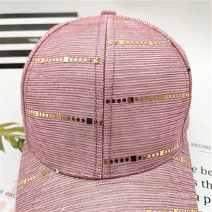 Close-up of pink fabric baseball cap featuring decorative gold sequins and glitter texture
