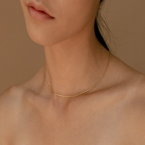 Close-up of minimalist 18K gold plated stainless steel snake chain on female collarbone