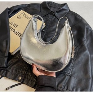 Detail of silver crescent moon bag with metallic finish on black leather background