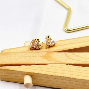 Macro shot of elegant pink teardrop zircon earrings on a minimalist wooden stand