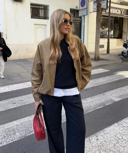 Close-up of a khaki oversized bomber jacket paired with a red leather handbag on a street