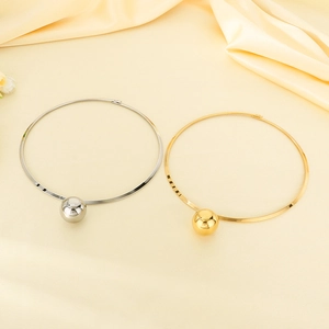 Polished silver and 18k gold plated stainless steel collar necklaces on beige silk fabric
