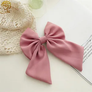 Detailed macro view of an elegant oversized dusty pink fabric bow hair clip with matte twill