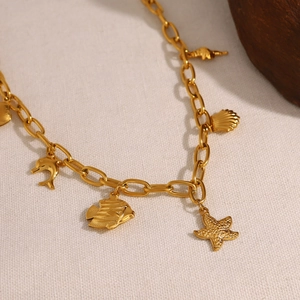 18K gold plated starfish shell and ocean charms necklace on textured fabric