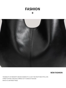 Close-up of black leather tote bag showing curved top edge and fine stitching detail