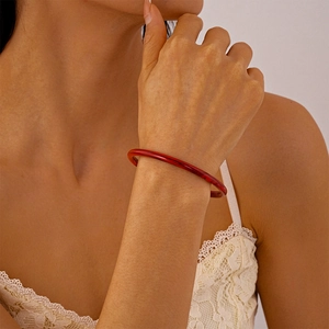 Gros plan d'un bracelet jonc en acrylique rouge translucide porté au poignet d'un modèle