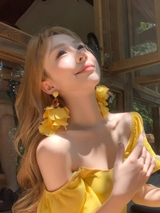 Détail de boucles d'oreilles fleurs en tissu jaune sur modèle avec un style luxueux d'été