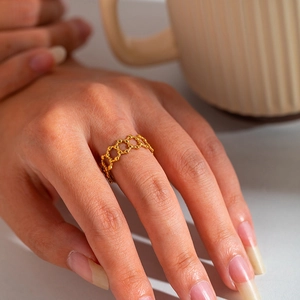 Detailed close-up of an 18K gold honeycomb geometric ring worn on a finger