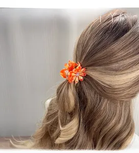 Détail de la pince à cheveux marguerite en acétate orange avec cristal central