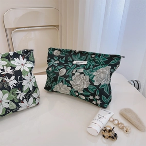 Detail showing two floral jacquard cosmetic bags with top zipper and woven label