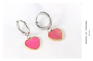 Macro shot of silver heart hoop earrings with glitter pink pendant on white texture