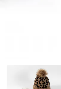 Détail du bonnet en maille léopard avec bord côtelé et pompon en fausse fourrure