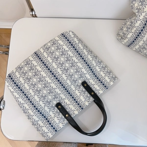 Close-up of floral cotton tote bag with blue patterns and black leather handle detail