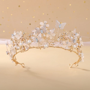 Macro detail of golden baroque crown featuring white floral accents and crystal butterflies