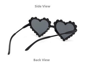 Detail view of heart-shaped kids sunglasses with unique wavy frames and grey lenses