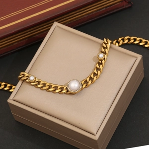 Detail of gold Cuban chain necklace with a large rhinestone halo pearl on jewelry box