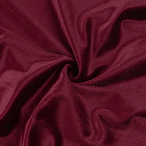 Macro del tessuto in velluto rosso vino che mostra consistenza morbida e lucentezza satinata