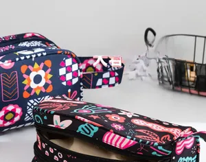 Détail de grandes trousses de maquillage avec motifs floraux géométriques et double zip