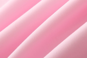Macro shot of soft pink cotton fabric showing fine textile texture and natural folds