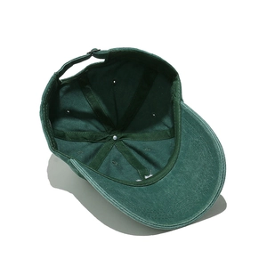 Detail of dark green cotton baseball cap showing inner stitching and metal adjuster