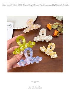 Detail of acetate flower hair claws with rhinestones in five pastel colors on wood