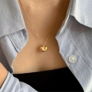 Close-up of a 925 sterling silver golden heart pendant necklace worn by a model