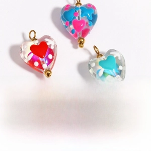 Macro view of heart-shaped glass beads with glossy finish and metal hooks for jewelry