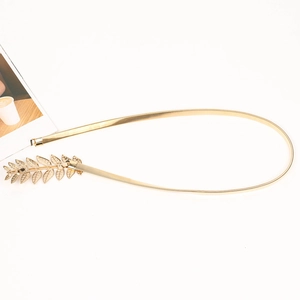 Detailed view of elegant gold metal elastic waist belt with leaf-shaped buckle closure