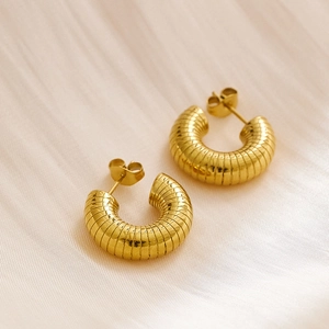 Detail of gold-plated titanium C-shape earrings with a textured serpent scale pattern