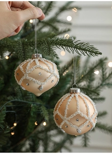 Close-up of champagne gold frosted Christmas ball ornament with white beads and rhinestones