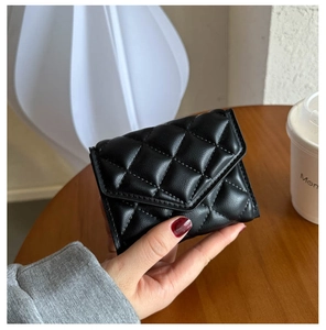 Detail of a black quilted leather mini purse with classic diamond pattern texture