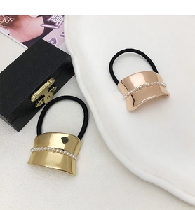 Detail of gold and rose gold metal hair rings with pearl accents on black elastic bands