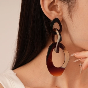 Close-up of tortoise shell resin geometric link earrings worn by a model