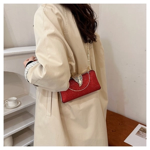 Elegant red evening clutch bag with gold leaf clasp worn with a chain strap