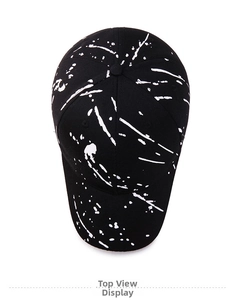 Top-down view of a black baseball cap featuring artistic white paint splatter design