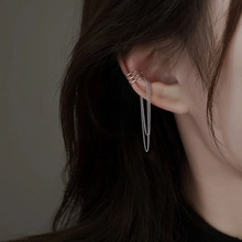 Detail of silver snake-style ear cuff with layered metal rings and long hanging chain