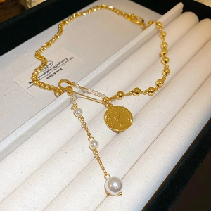 Detailed shot of retro gold portrait coin pendant and faux pearl chain necklace