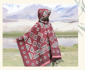 Détail d'un poncho rouge à capuche ethnique avec motifs géométriques et franges